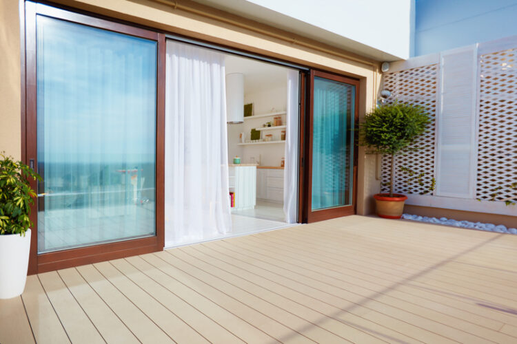 A wooden deck with sliding glass doors and a privacy screen to the patio.